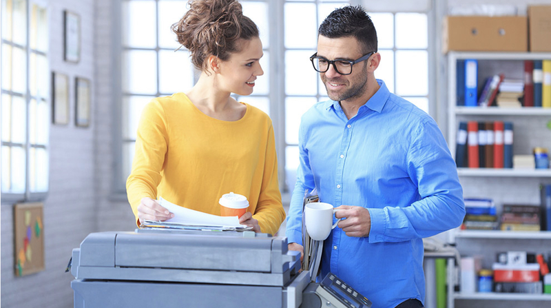 Ein Mann und eine Frau stehen an einem Druckgerät im Büro