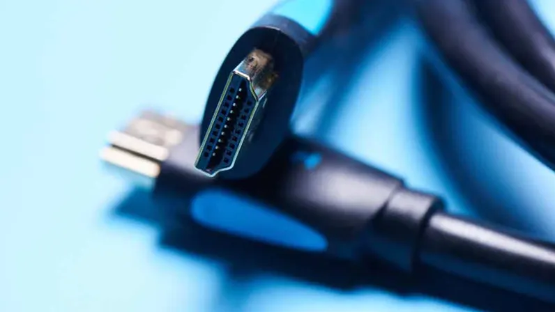 Nahaufnahme von zwei schwarzen HDMI-Kabeln mit blauen Akzenten auf hellblauem Grund.