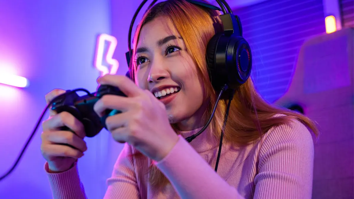 Eine Frau zockt mit einem Controller und trägt dabei ein Gaming-Headset