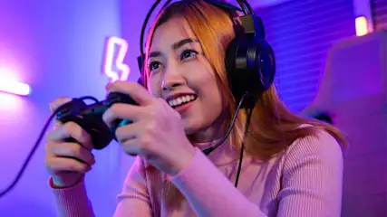 Eine Frau zockt mit einem Controller und trägt dabei ein Gaming-Headset