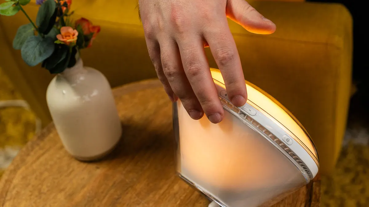 Eine Hand berührt einen Knopf auf der Oberseite eines Lichtweckers.