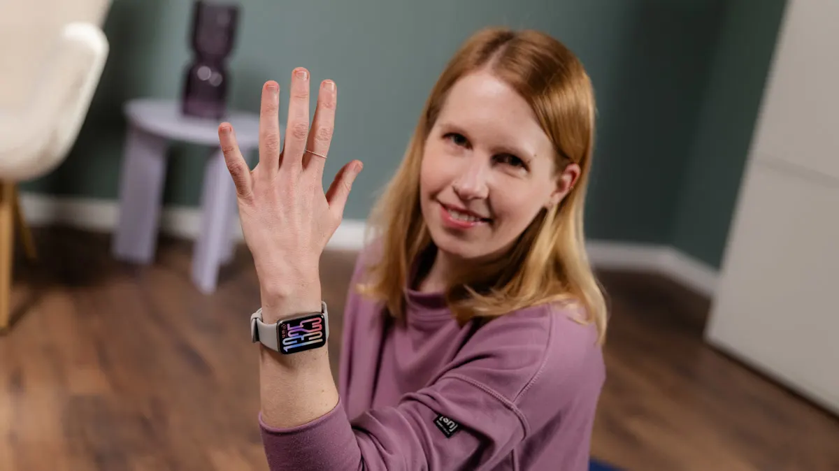 Franzi trägt das Xiaomi Smart Band 9 Pro am linken Handgelenk und hält den Arm hoch.