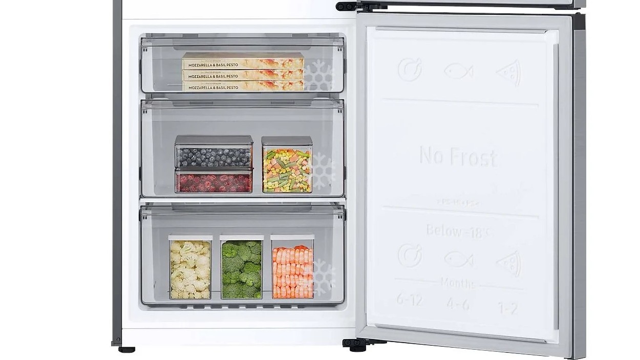 Offener Gefrierschrank der SAMSUNG RL38C775CS9/EG Kühlgefrierkombination mit drei Schubladen, gefüllt mit Tiefkühlpizzen, Beeren, Gemüse und Garnelen.