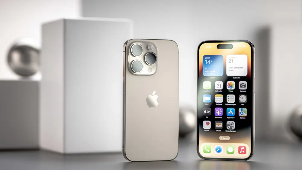 Zwei iPhones stehen auf einem Tisch. Das linke zeigt die Rückseite, das rechte den Bildschirm mit Apps. Im Hintergrund sind geometrische Formen.