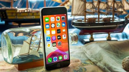 Ein iPhone SE steht angelehnt an einem Buddelschiff.