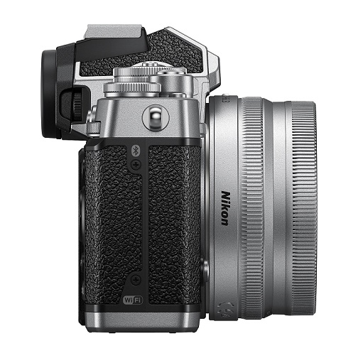 Eine silberne Nikon-Kamera mit schwarzem, strukturiertem Griff und silbernem Objektiv, seitlich aufgenommen.