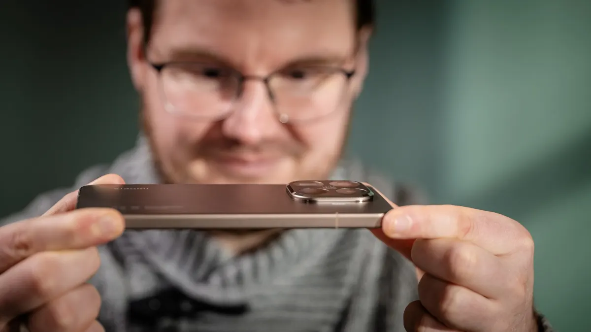 Michael hält das Smartphone Xiaomi 15T Pro zwischen seinen Fingern und fokussiert seinen Blick auf das Kameramodul.