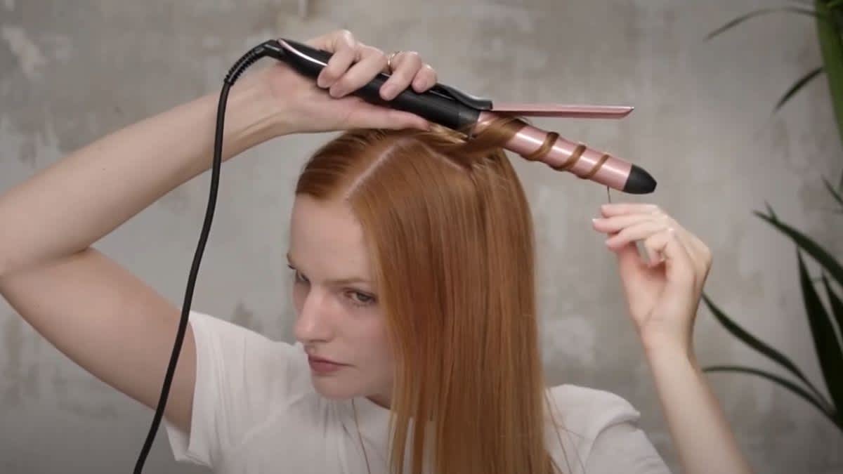 Eine Frau lockt sich die Haare mit dem BaByliss C451E.