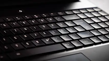 Nahaufnahme einer schwarzen Laptop-Tastatur mit weißen Buchstaben und Symbolen auf den Tasten.