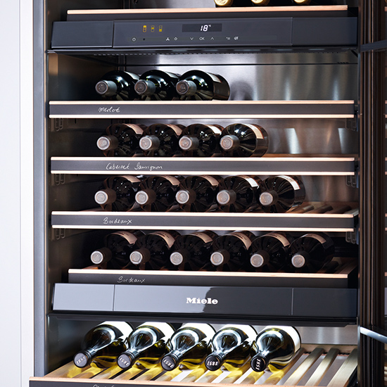 Ein Weinkühlschrank mit mehreren Regalen. Die Regale sind mit Weinflaschen gefüllt. Die Temperaturanzeige zeigt 18 Grad.