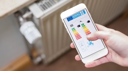 hand_mit_smartphone_vor_heizung_energielabel