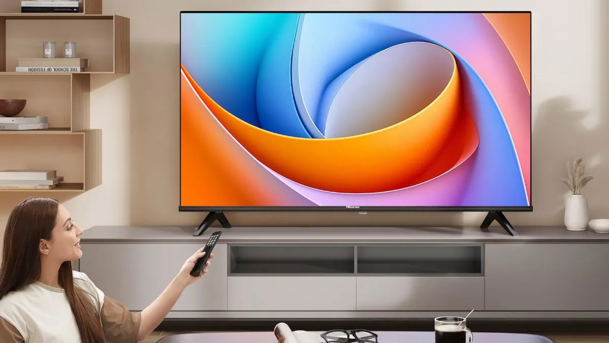 Eine Frau schaltet den Fernseher Hisense A4Q mit einer Fernbedienung ein.