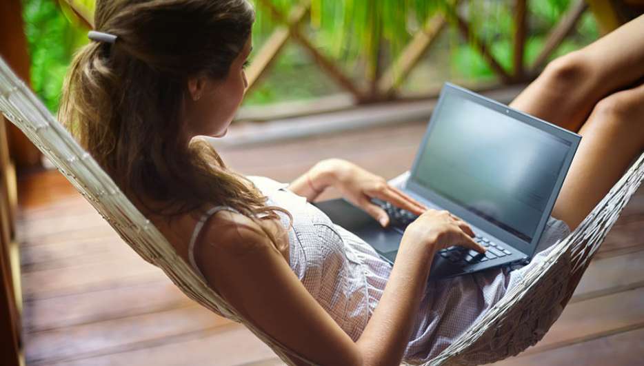 Eine Frau mit Laptop liegt in einer Hängematte.