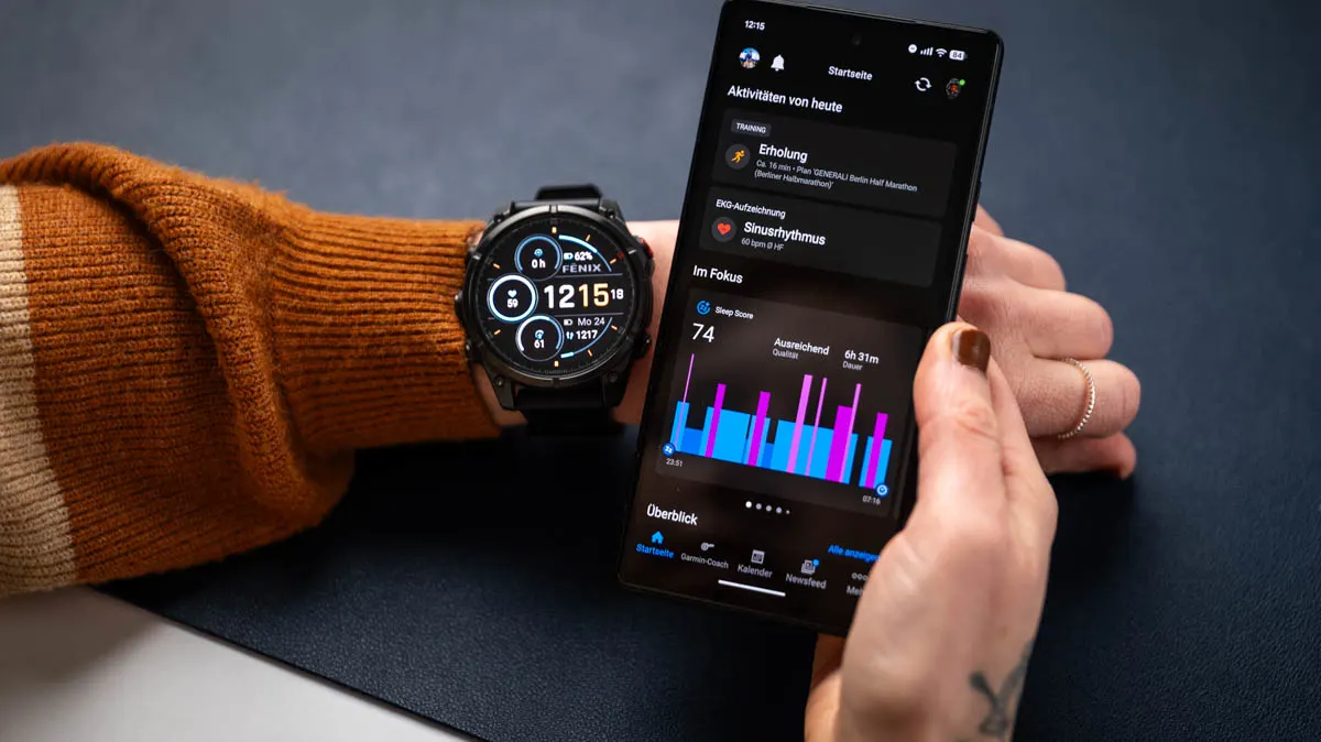 Franzi schaut sich die Startseite der Garmin-Connect-App auf dem Smartphone an, am linken Arm trägt sie die Garmin Fenix 8 Pro.