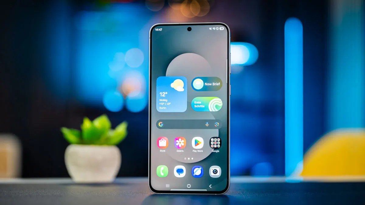 Das Smartphone Samsung Galaxy S25 FE steht mit eingeschaltetem Display auf einem Tisch.