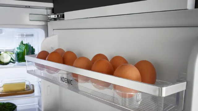 Eierablage mit frischen Eiern in der Tür des KBK 8811 E DOD Einbaukühlschranks, Innenraum mit weiteren Lebensmitteln.