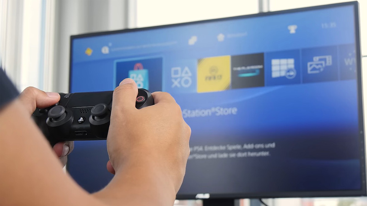 Person mit Playstation-Controller in der Hand sitzt vor Monitor mit dem Screen des PlayStation Stores.