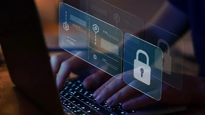Eine Person tippt auf einem Laptop, überlagert mit digitalen Datensymbolen und einem weißen Vorhängeschloss-Symbol.