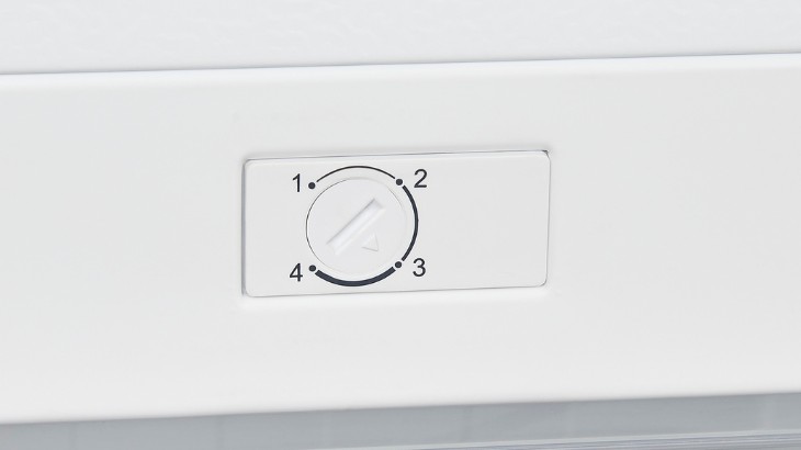 Weiße Oberfläche mit einem weißen, rechteckigen Bedienfeld. Auf dem Bedienfeld befindet sich ein Drehknopf mit den Zahlen 1 bis 4.