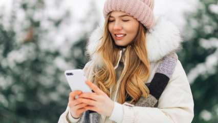 Frau benutzt Smartphone in winterlicher Umgebung.