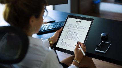 Geschäftsfrau liest einen Lebenslauf auf einem digitalen Tablet, um das richtige Personal einzustellen