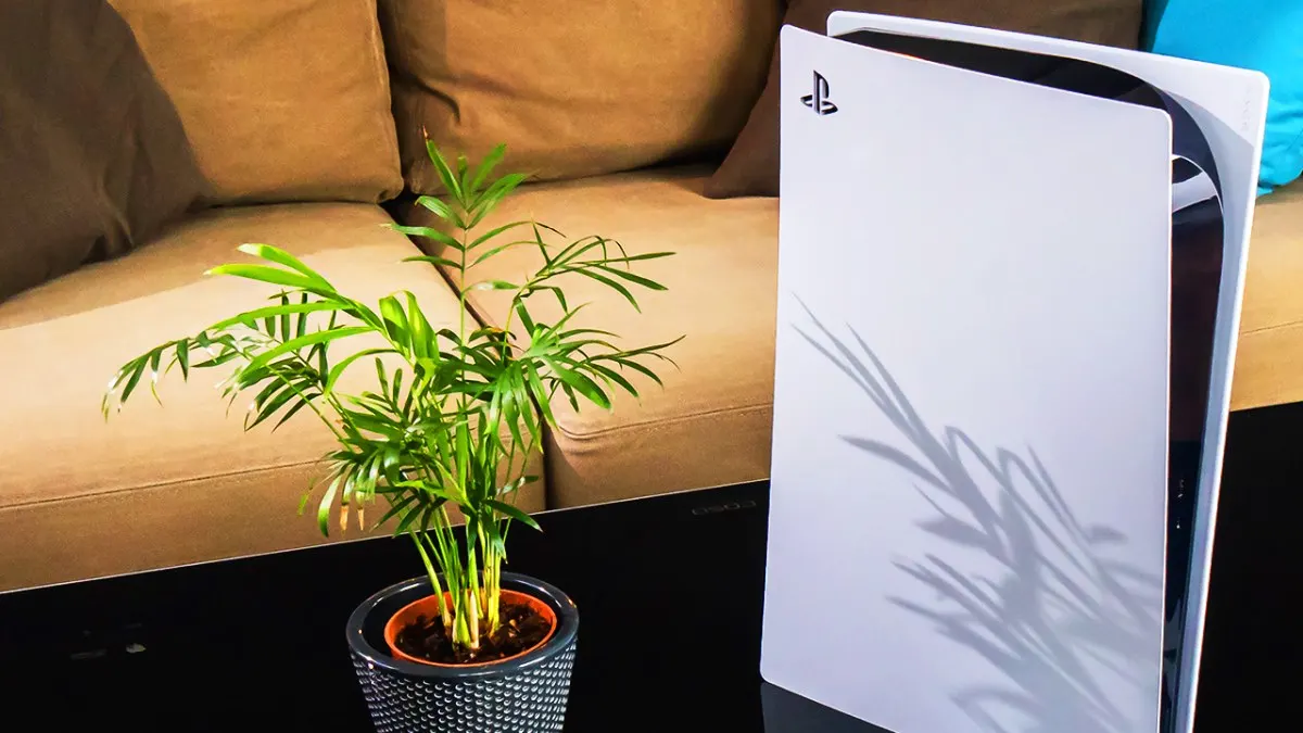 Eine PS5 steht neben einer Zimmerpflanze auf einem Couchtisch.
