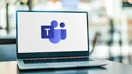 Ein Laptop zeigt das Microsoft Teams-Logo auf dem Bildschirm. Das Logo ist blau und besteht aus einem T und Kreisen.