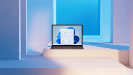 Ein Laptop steht auf einer weißen Plattform vor einem blauen Hintergrund. Auf dem Bildschirm ist ein Menü mit Symbolen.