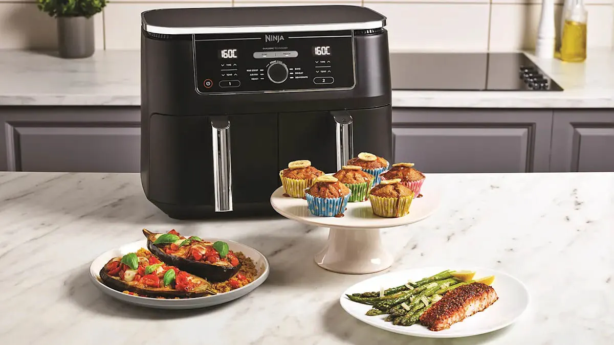 Die Heißluftfritteuse Ninja AF400EU in einer hellen Küche. Vor der Fritteuse stehen verschiedene Speisen.