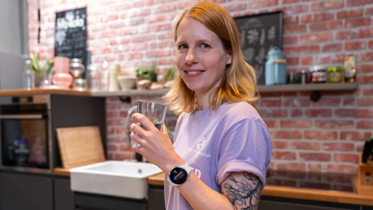 Franzi trägt die Samsung Galaxy Watch8 und holt sich ein Glas Wasser aus der Küche.