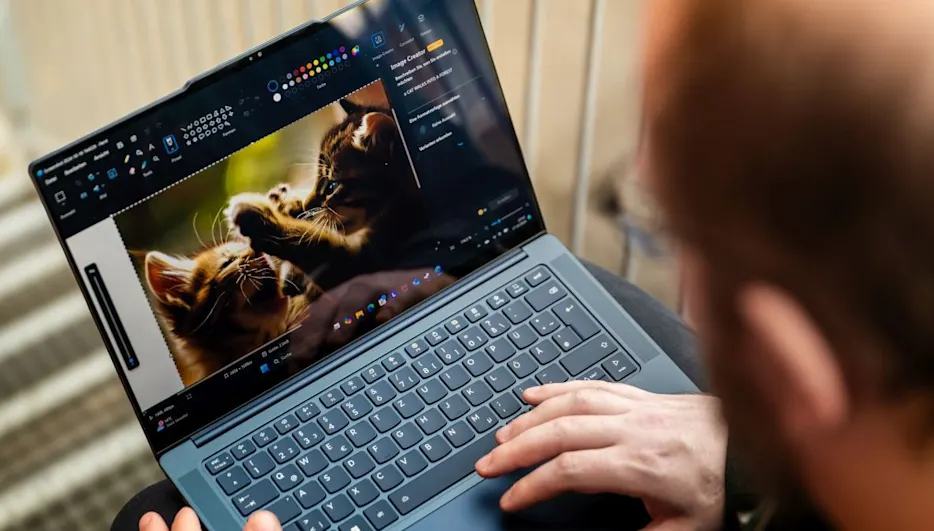 Eine Person tippt auf einem Laptop. Auf dem Bildschirm sind zwei spielende Kätzchen zu sehen, mit Bearbeitungswerkzeugen an den Seiten.