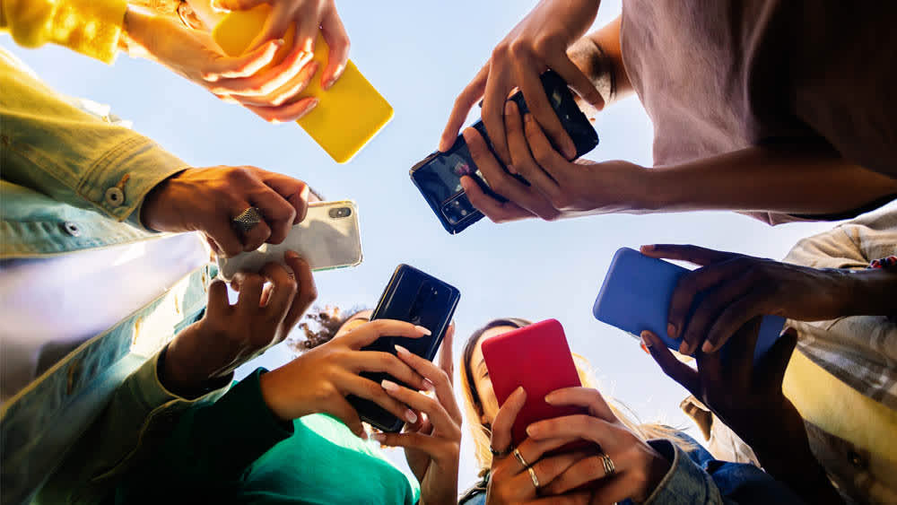 Mehrere Personen stehen zusammen in einem Kreis mit ihren Smartphones in den Händen.