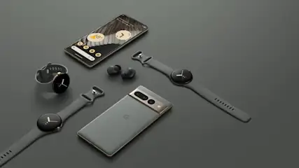 Zwei Smartphones, zwei Smartwatches und Ohrhörer auf einem grauen Hintergrund. Ein Telefon liegt mit dem Bildschirm nach oben.