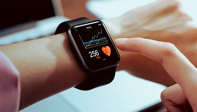 Schwarze Smartwatch am Handgelenk mit Anzeige von Kalorienverbrauch, Herzfrequenz und Aktivitätsdiagramm. Finger berührt den Bildschirm.