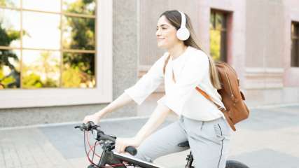 Eine Frau mit Kopfhörern auf dem Kopf sitzt auf einem Fahrrad.
