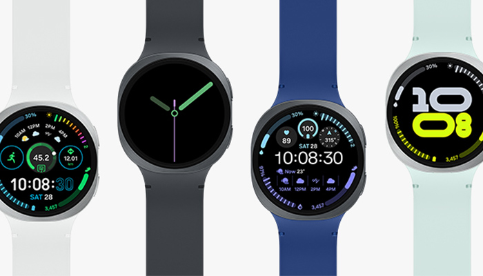 Vier nebeneinander liegende Smartwatches mit unterschiedlichen farbigen Armbändern.