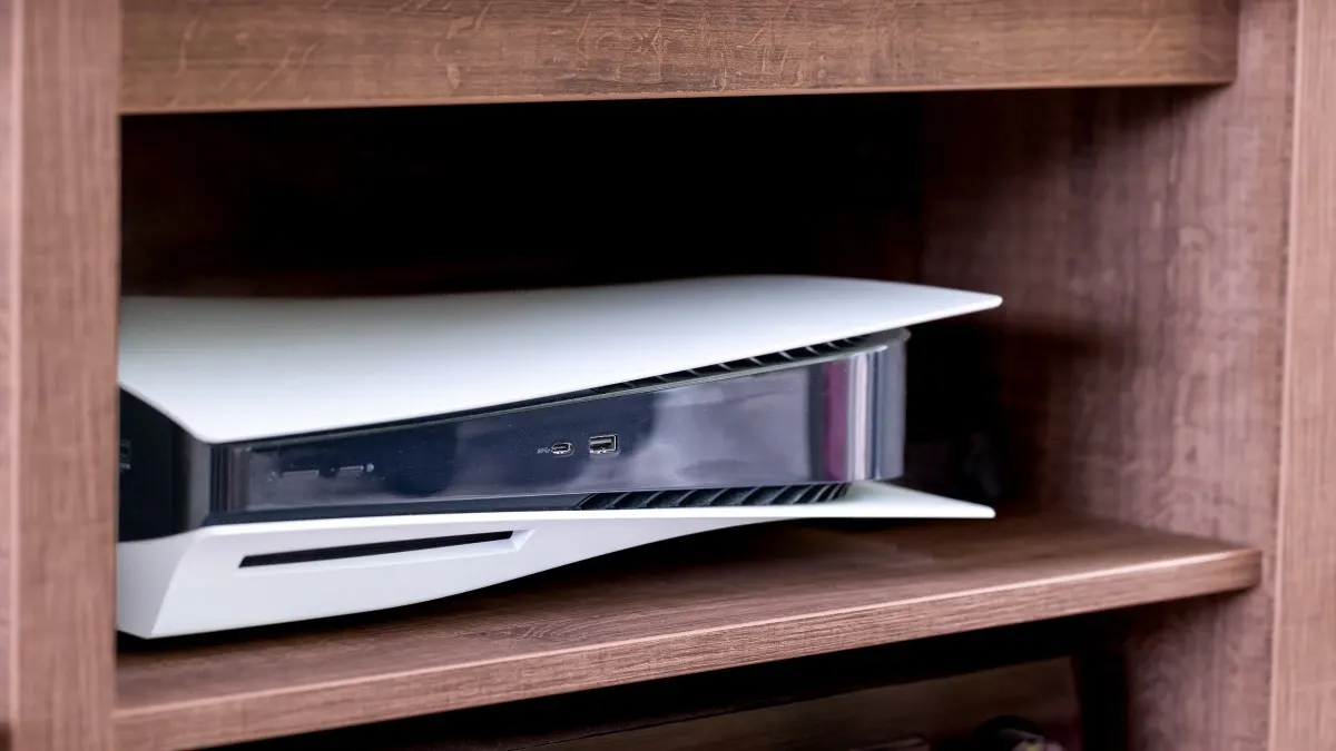 Eine PlayStation 5 liegt in einem kleinem Fach.