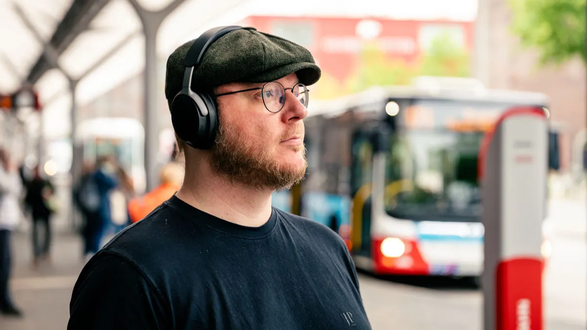 Andreas trägt den Bose QuietComfort Ultra an einer Bushaltestelle.