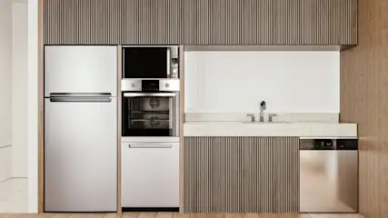 Weiße Küche mit Kühlschrank, Backofen, Spüle und Geschirrspüler. Holzpaneele an Schränken und Wänden. Helle Arbeitsplatte.