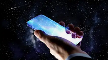 Eine Hand hält ein blau leuchtendes Smartphone vor einem dunklen Nachthimmel voller Sterne und Sternschnuppen.