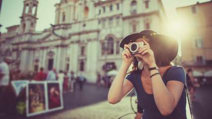 Eine Frau macht ein Foto in der Stadt mit einer Kompaktkamera.