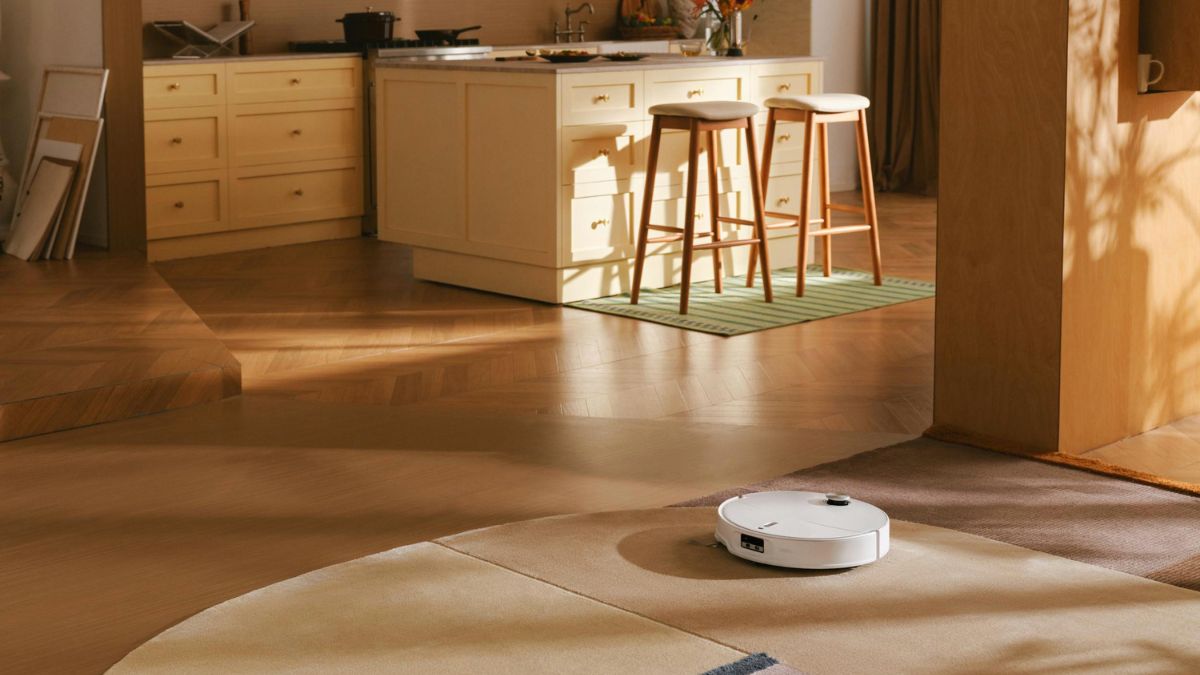 Der Saugroboter Roborock Qrevo Curv 2 ProX saugt auf einem Teppich in einer Wohnküche.