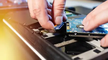 Eine Person baut eine Festplatte in einen Laptop ein.