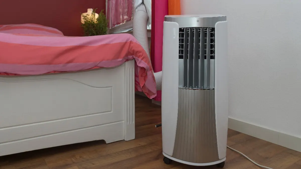 Ein Monoblock-Klimagerät steht neben einem Bett.