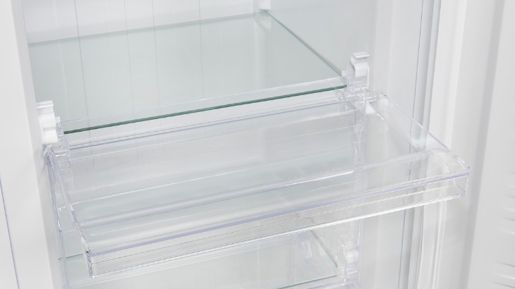 Im Inneren eines weißen Kühlschranks befinden sich durchsichtige Glas- und Plastikregale.