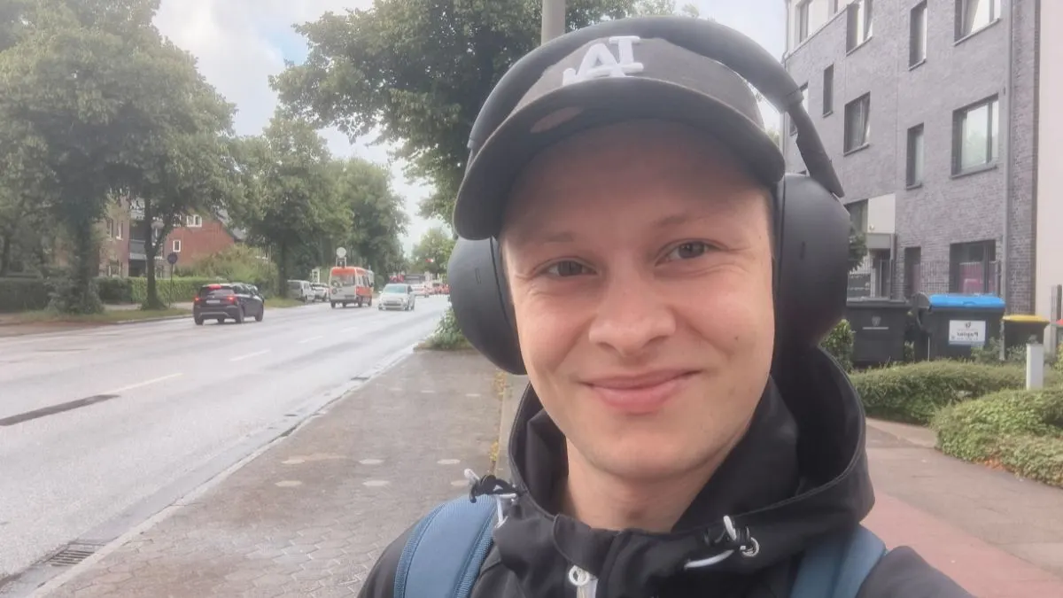 Ein Selfie von Alex, der an einer Straße steht und den Kopfhörer Sony WH-1000XM6 trägt.