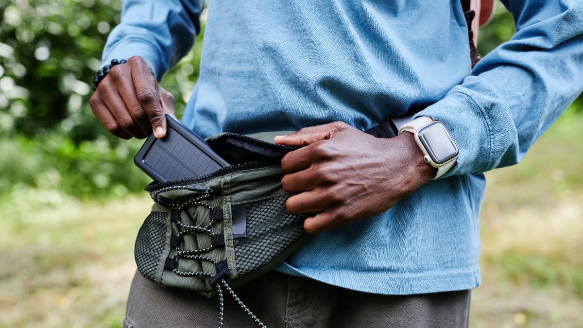 Ein Mann zieht eine Solar-Powerbank aus der Bauchtasche.