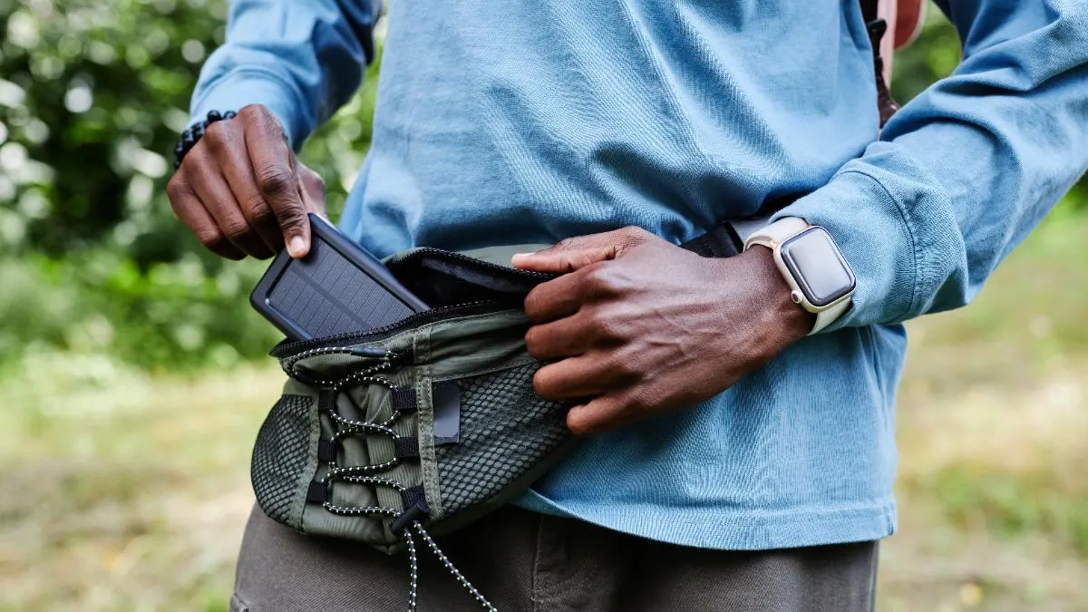 Ein Mann zieht eine Solar-Powerbank aus der Bauchtasche.