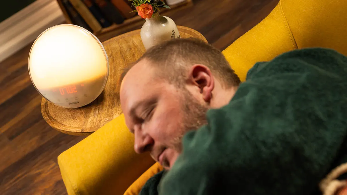 Andreas liegt auf einer Couch, auf einem Beistelltisch steht ein Philips-Lichtwecker.