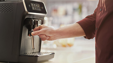 PHILIPS EP2220/40 Serie 2200 Kaffeevollautomat Seitenansicht mit Display und Milchdüse von einer Hand bedient